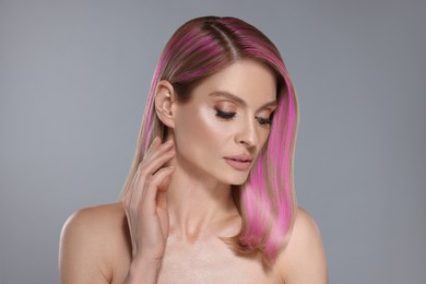 Hair styling. Gorgeous woman with colorful hair on grey background