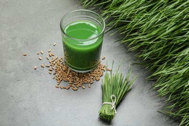 Photo of Composition with glass of wheat grass juice on grey stone background