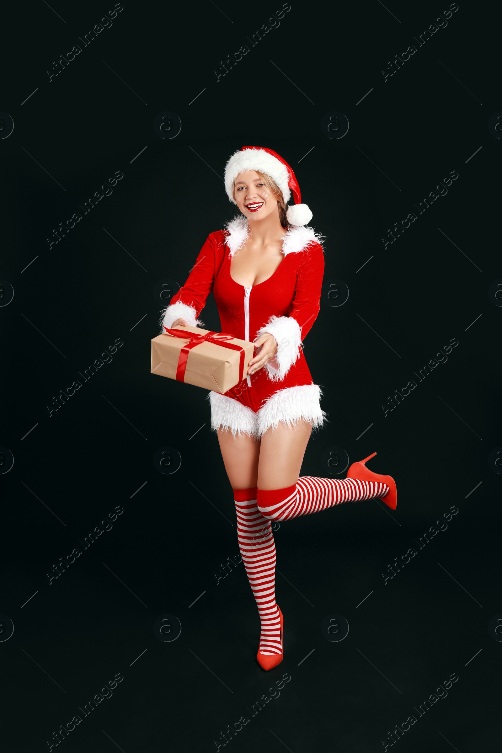 Photo of Beautiful Santa girl with Christmas gift on black background