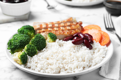 Photo of Delicious rice with beans and meat served on white marble table, closeup