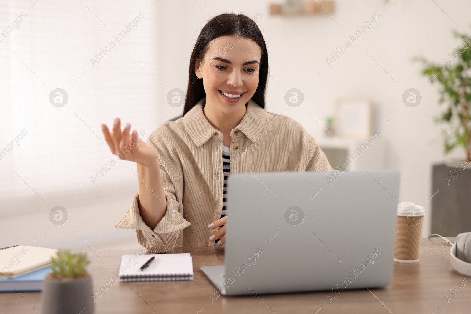 Photo of Young woman using video chat during webinar at table in room