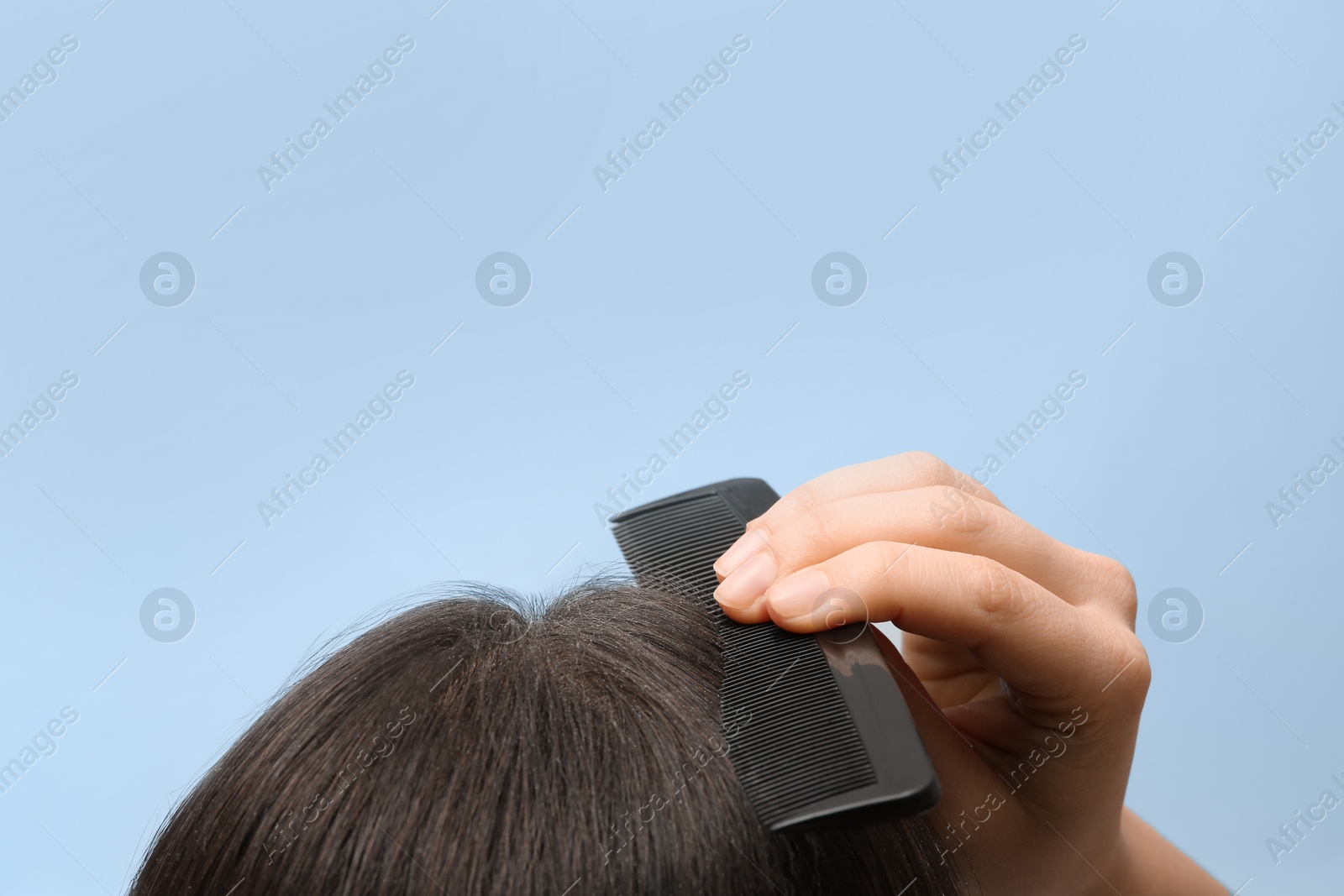 Photo of Woman with comb and dandruff in her dark hair on color background, closeup. Space for text