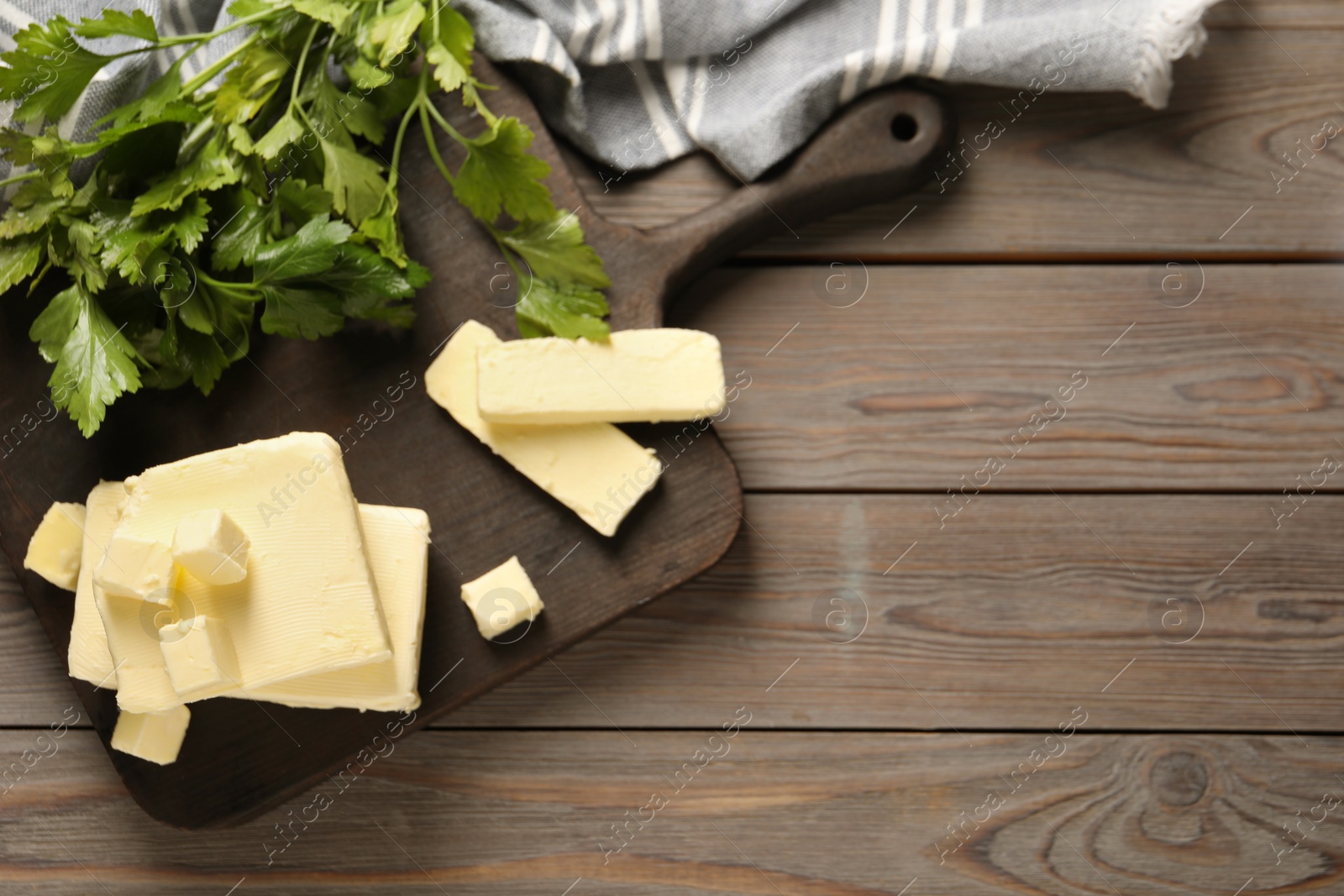 Photo of Tasty butter and parsley on wooden table, top view. Space for text