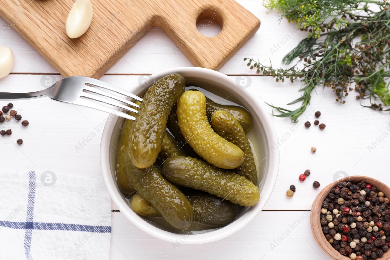 Photo of Tasty pickled cucumbers and ingredients on white wooden table, flat lay