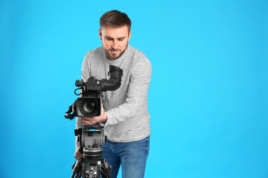 Operator with professional video camera on blue background, space for text