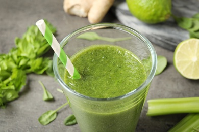 Photo of Green juice and fresh ingredients on grey table, closeup