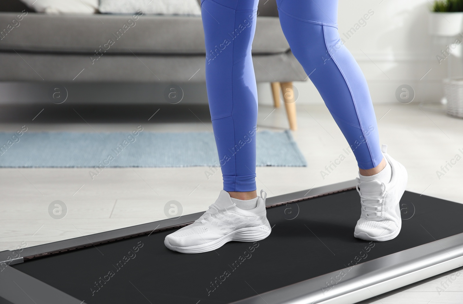 Photo of Sporty woman training on walking treadmill at home, closeup