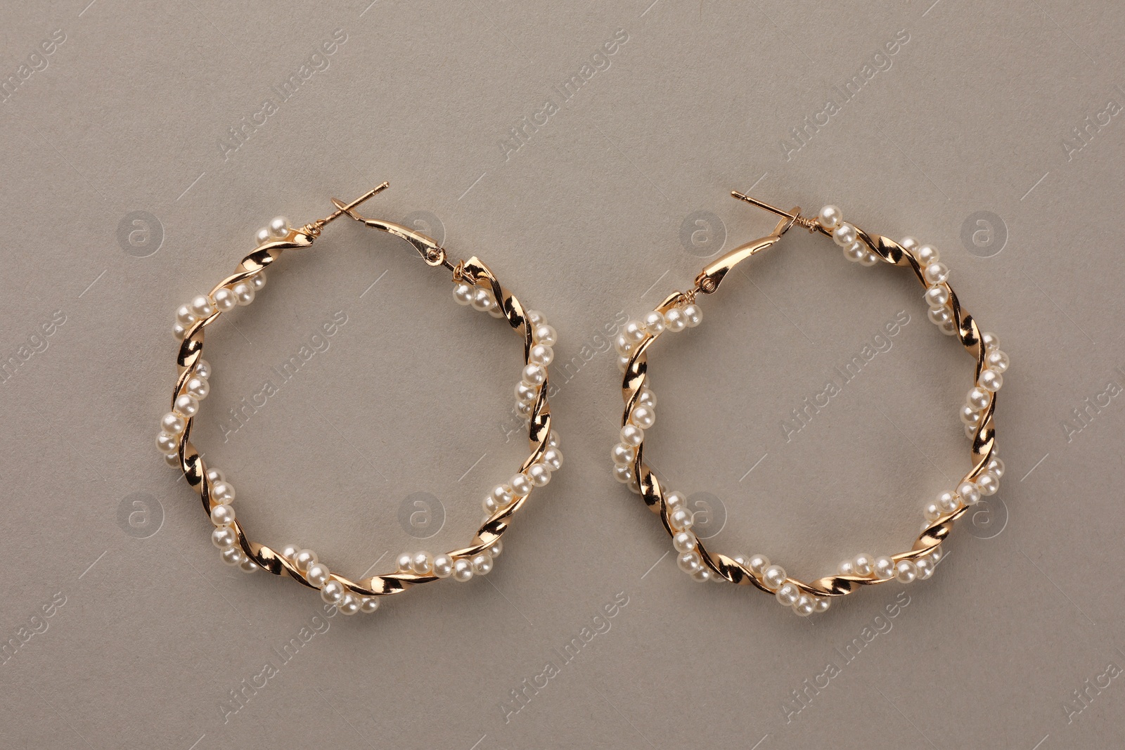 Photo of Elegant earrings with pearls on beige background, top view