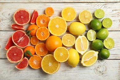 Different citrus fruits on wooden background, top view