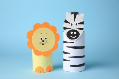 Photo of Toy lion and zebra made from toilet paper hubs on light blue background. Children's handmade ideas