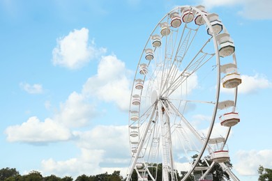 Large white observation wheel against sky, space for text