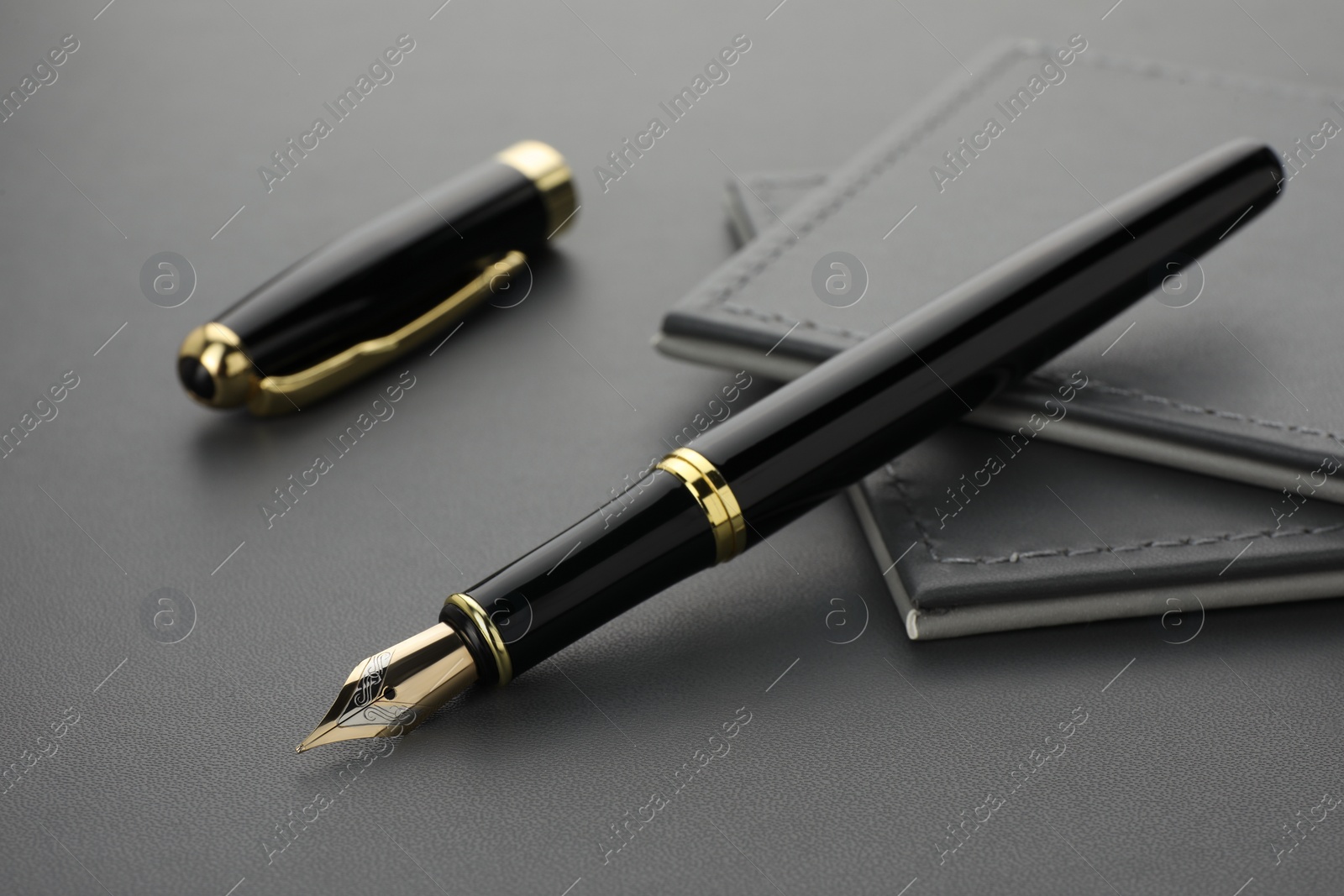 Photo of Stylish black fountain pen on grey textured table, closeup