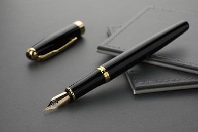 Stylish black fountain pen on grey textured table, closeup