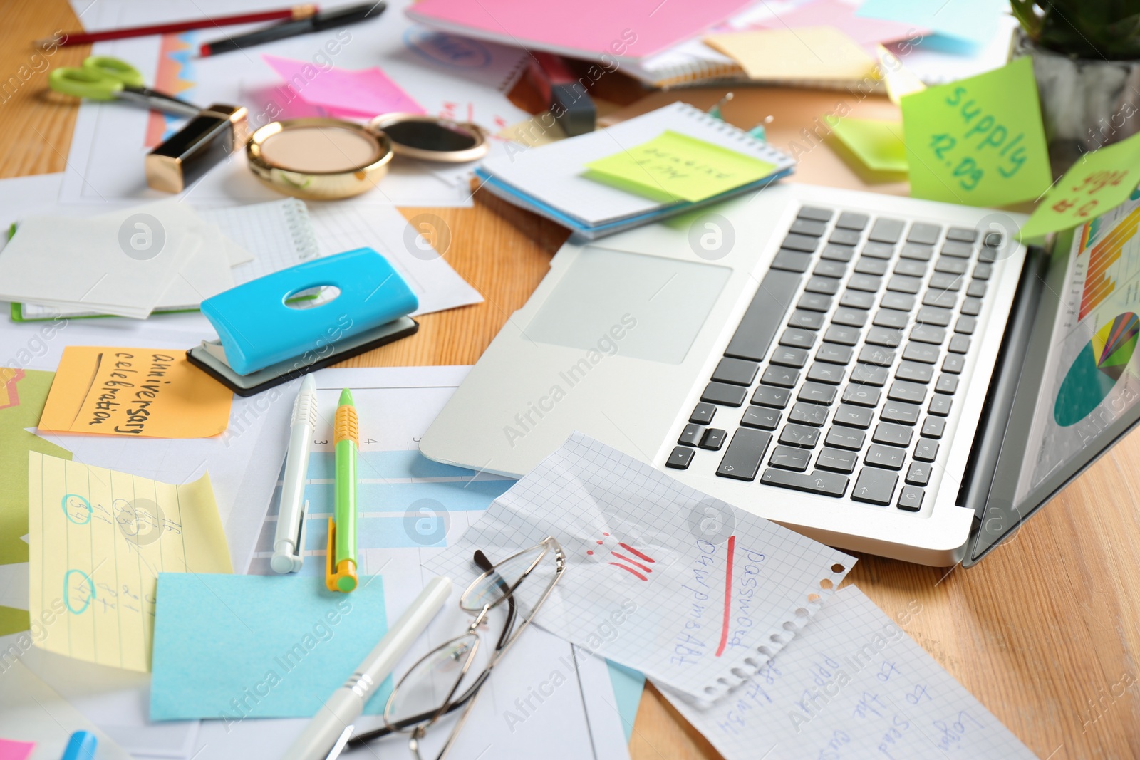 Photo of Messy table with laptop and stationery. Concept of being overwhelmed by work