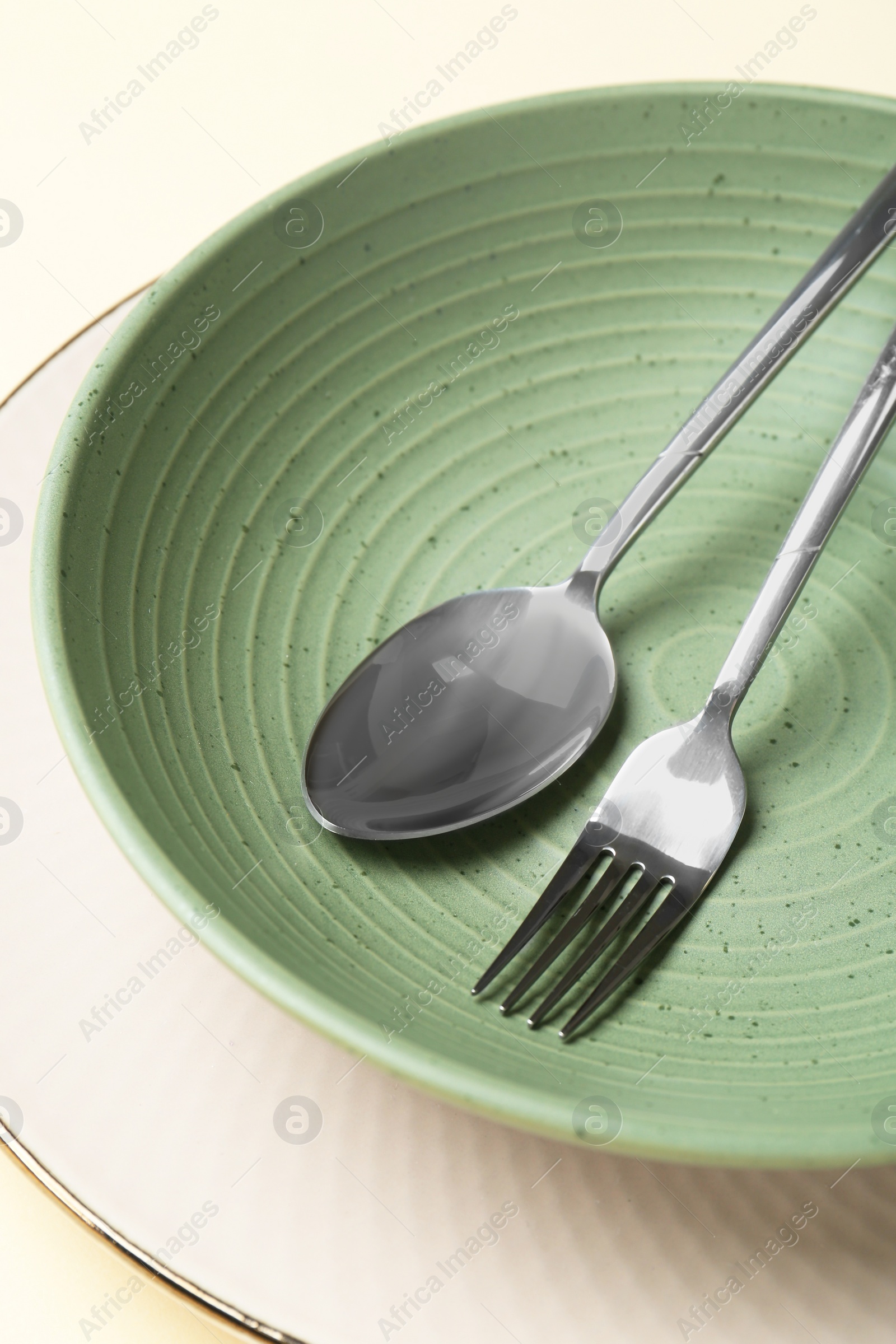 Photo of Stylish ceramic plate, bowl and cutlery on beige background, closeup