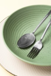 Stylish ceramic plate, bowl and cutlery on beige background, closeup