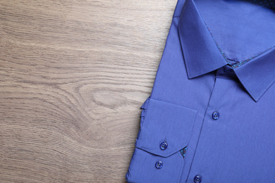 Photo of Stylish blue shirt on wooden table, top view with space for text. Dry-cleaning service