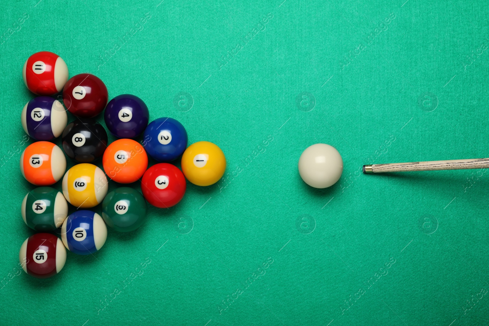 Photo of Set of billiard balls and cue on green table, flat lay