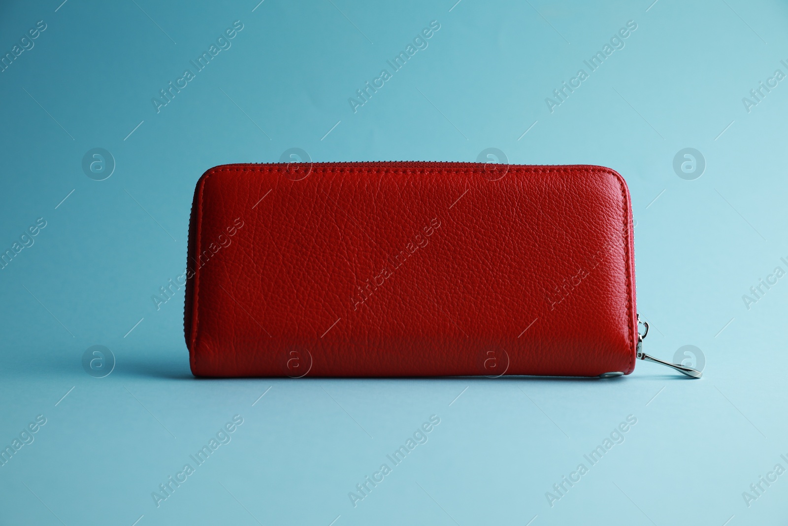 Photo of One stylish leather purse on light blue background