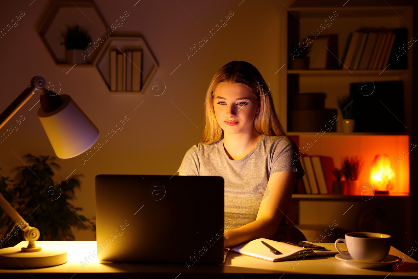 Photo of Home workplace. Woman working on laptop at white desk in room