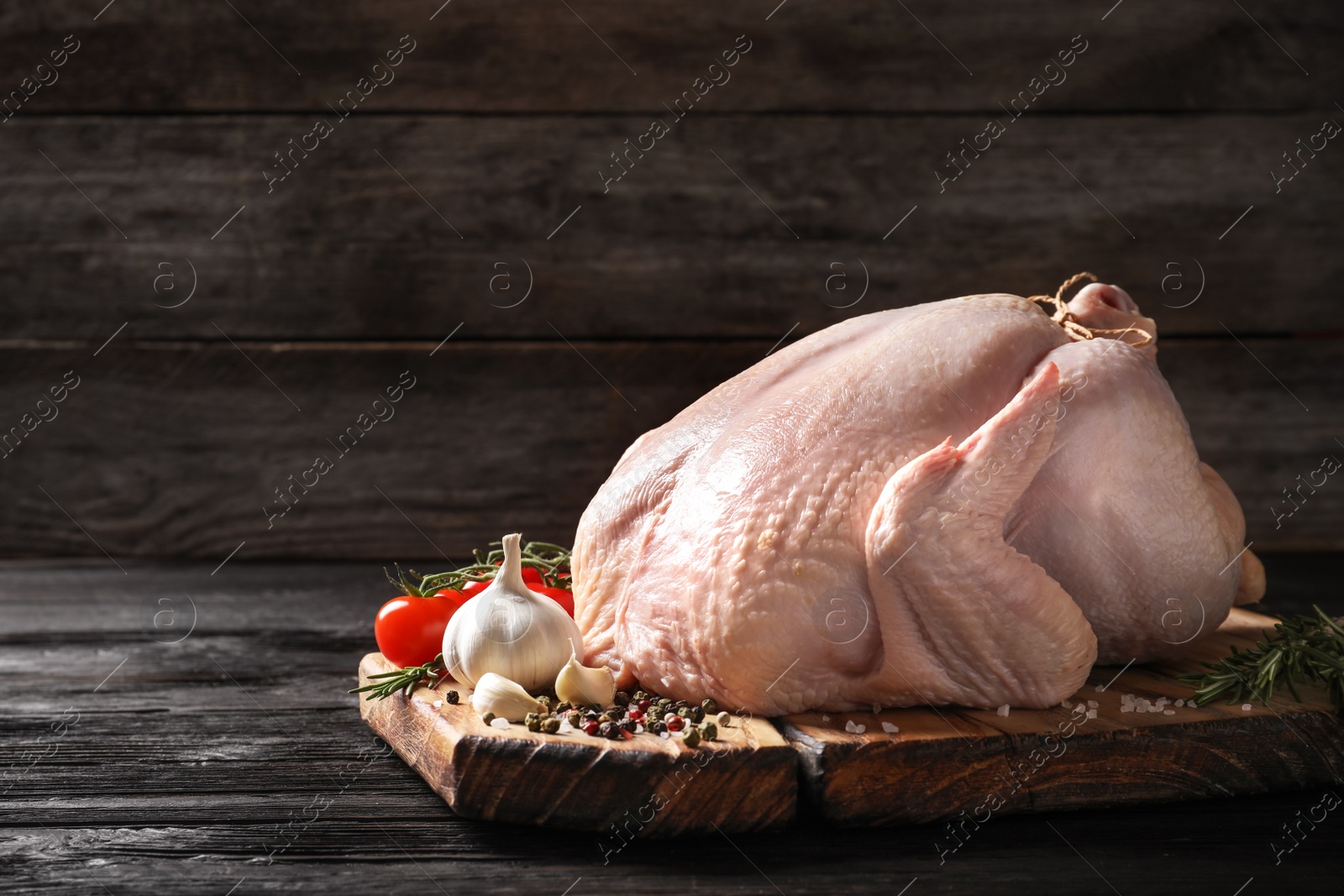 Photo of Board with raw turkey and ingredients on wooden table. Space for text