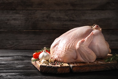 Photo of Board with raw turkey and ingredients on wooden table. Space for text