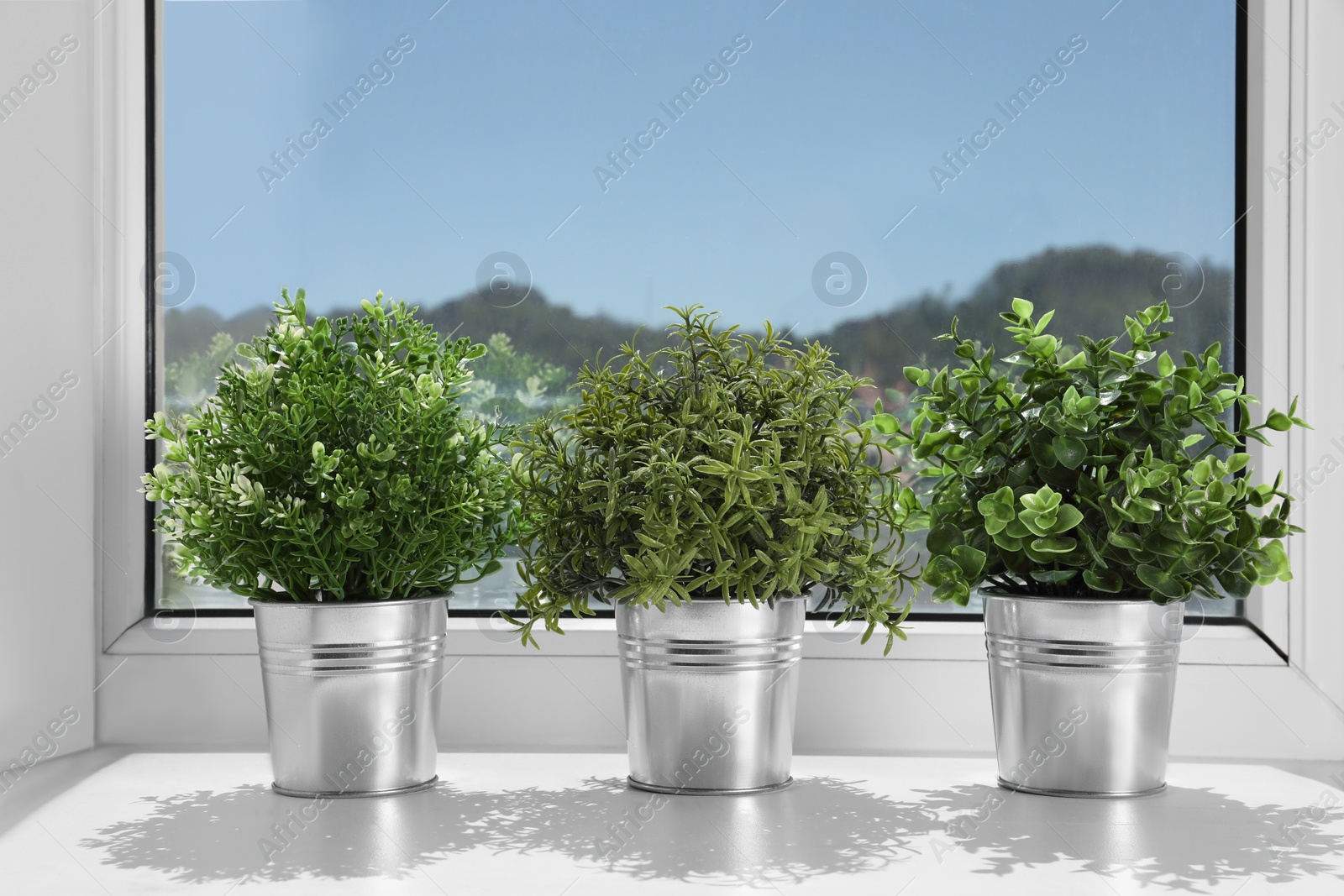 Photo of Artificial potted herbs on sunny day on windowsill indoors. Home decor