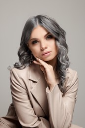 Portrait of beautiful woman with ash hair color on grey background