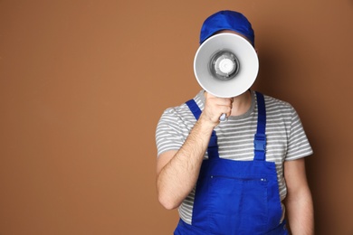 Male worker with megaphone on color background