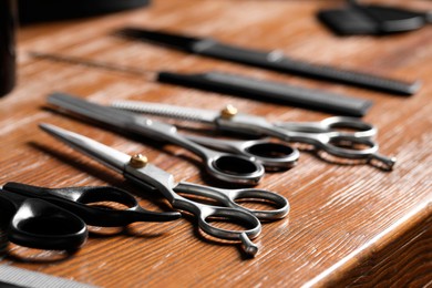 Hairdresser tools. Different scissors and combs on wooden table, closeup