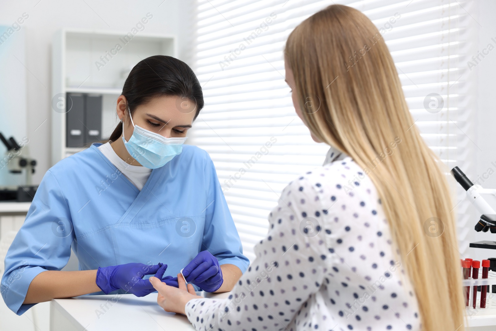 Photo of Laboratory testing. Doctor taking blood sample from patient at white table in hospital