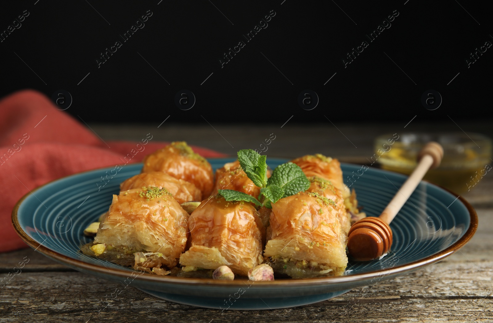 Photo of Delicious baklava with pistachios and mint on wooden table, closeup