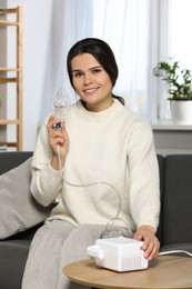Photo of Happy young woman with nebulizer at home