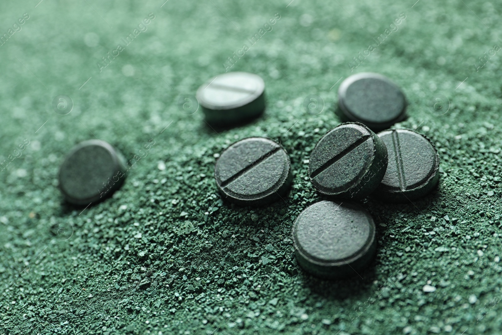 Photo of Natural green spirulina powder and pills as background, closeup