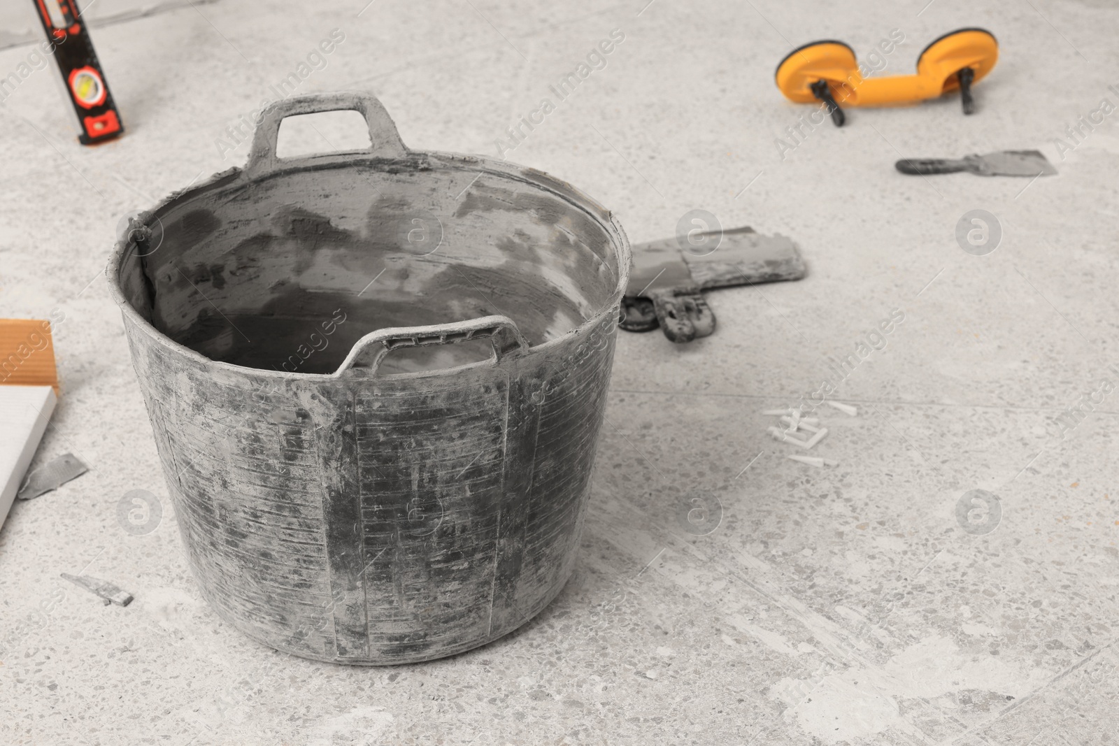 Photo of Bucket and different equipment on floor indoors. Tiles installation process