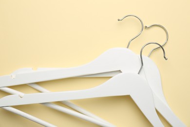 White hangers on pale yellow background, top view. Space for text