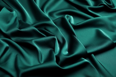 Crumpled dark green silk fabric as background, closeup