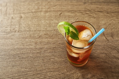 Glass of refreshing iced tea on wooden table. Space for text