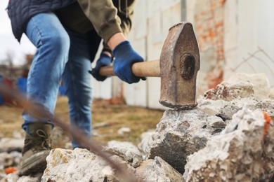 Man breaking stones with sledgehammer outdoors, closeup