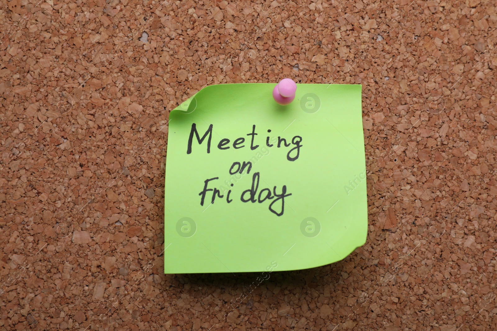 Photo of Paper note with words Meeting on Friday pinned to cork board