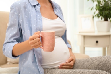 Photo of Pregnant woman drinking tea at home, closeup