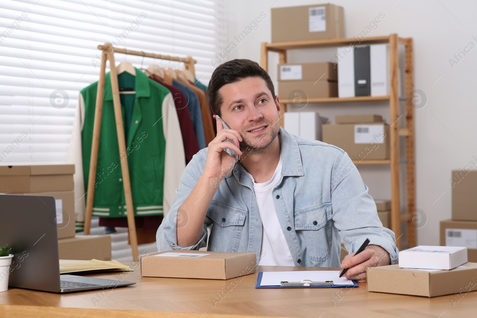 Photo of Seller talking on phone while working in office. Online store