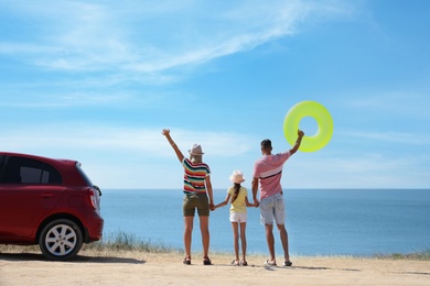 Happy family with inflatable ring near car at beach