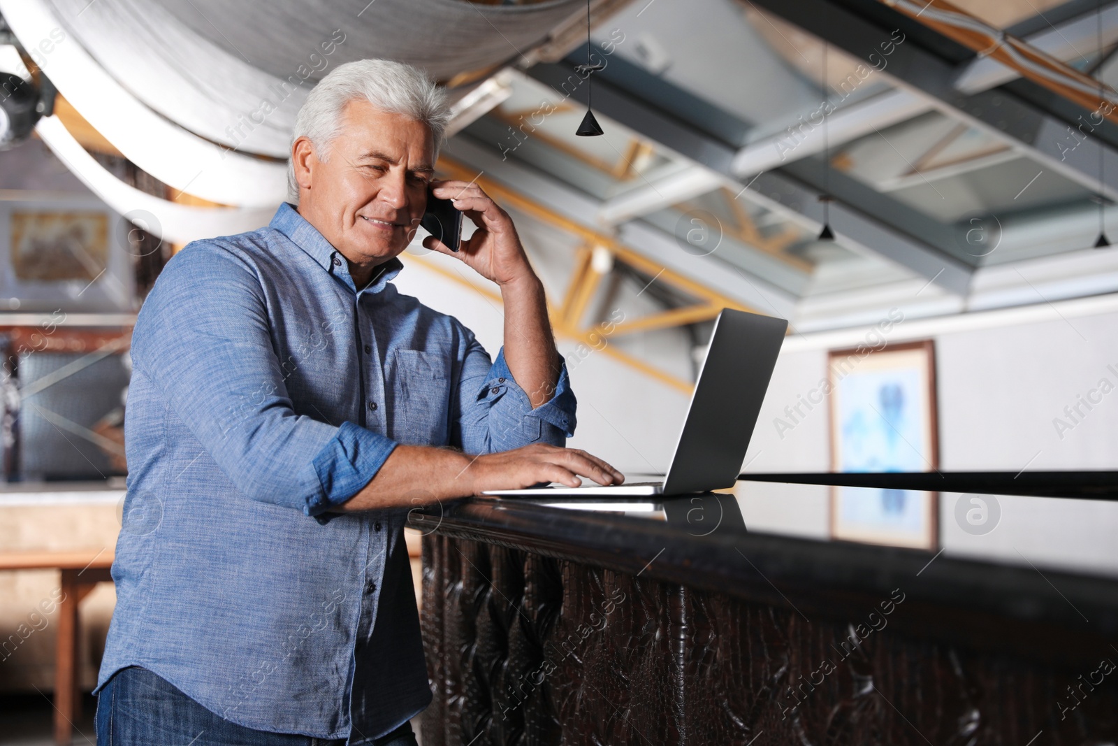 Photo of Senior business owner talking on phone in his restaurant