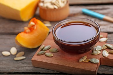 Fresh pumpkin seed oil in glass bowl on wooden table