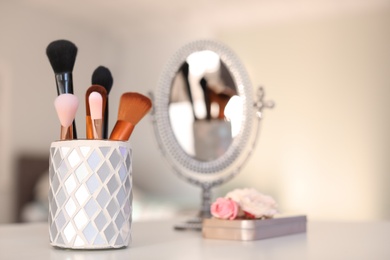 Holder with makeup brushes on table