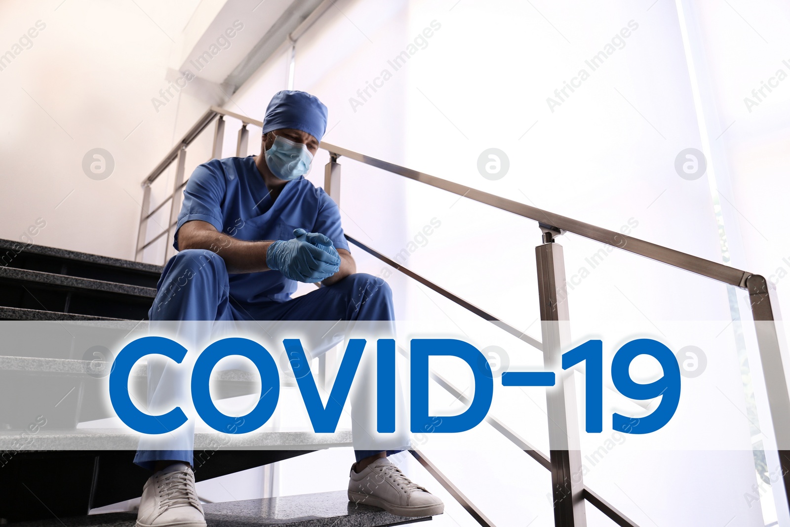 Image of Tired overwhelmed doctor sitting on stairs in hospital. Medical system collapse during coronavirus pandemic