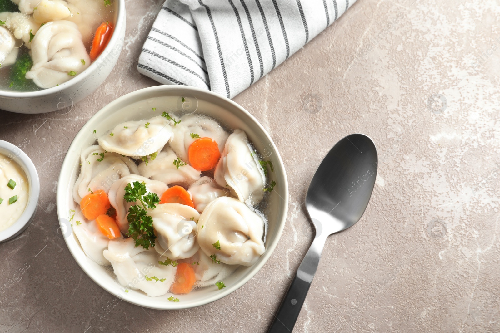 Photo of Tasty dumplings in broth served on grey marble table, flat lay. Space for text