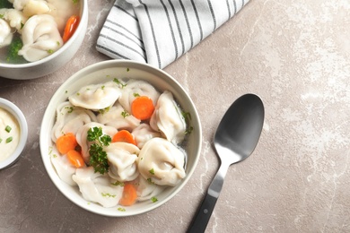 Photo of Tasty dumplings in broth served on grey marble table, flat lay. Space for text