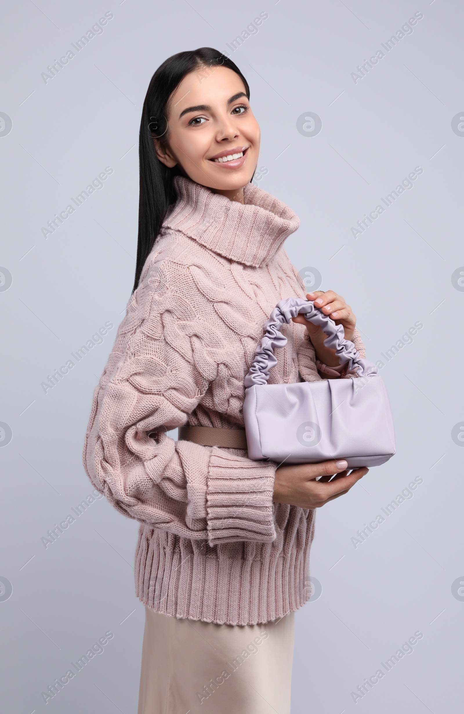 Photo of Fashionable young woman with stylish bag on light background